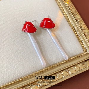 Vintage-style red mushroom earrings with white pearl pendants on an ornate frame