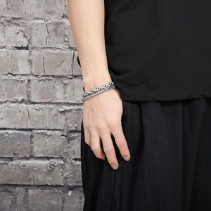 Detail of silver double wheat chain bracelet on male wrist against grey background