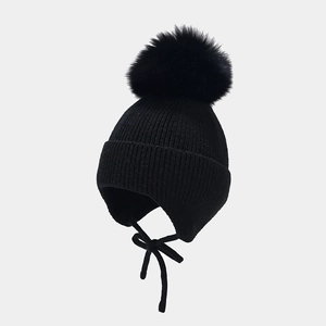 Texture de maille détaillée d'un bonnet d'hiver noir avec pompon en fourrure et liens