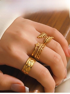 Detail showing four gold-toned adjustable rings with leaf, star, and textured patterns