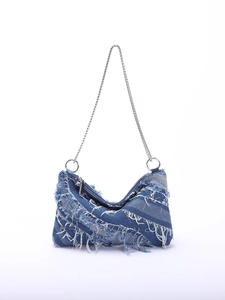 Close-up of patchwork denim shoulder bag with frayed fringe edges and silver chain strap