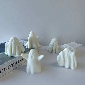 Detailed view of Halloween ghost silicone molds and finished white wax crafts on a book