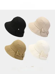 Detail of four textured bucket hats with bow decoration in black, khaki, and cream colors