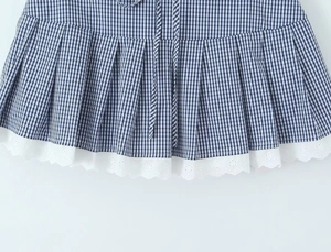 Close-up of pleated blue and white checkered skirt with delicate white lace trim hem