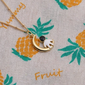 Gold moon necklace with astronaut pendant and bead chain on decorative fabric background