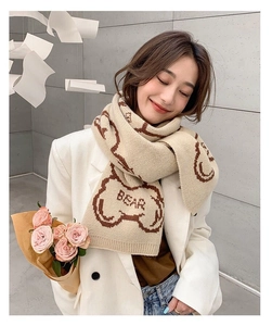 Close-up of beige knit scarf showing soft texture and cute brown bear patterns