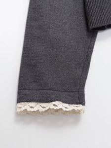 Détail des poignets d'un pull en maille gris foncé avec bordure en dentelle blanche