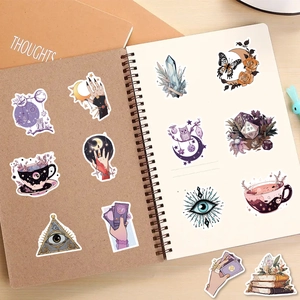 Detail of bohemian witch stickers featuring tarot crystals and moons on a wooden desk
