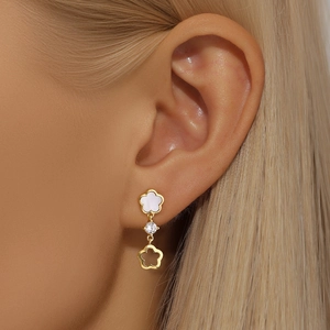 Gros plan sur d'élégantes boucles d'oreilles fleur en argent s925 et nacre sur modèle