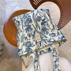Detailed close-up of a botanical print canvas tote bag hanging on a vintage wooden chair