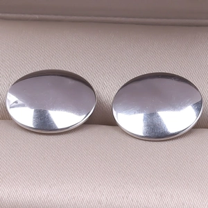 Macro view of mirror polished oval silver stainless steel earrings in a premium jewelry box
