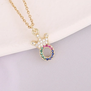 Detail of 18K gold necklace featuring a rainbow zircon crown pendant on a white plate