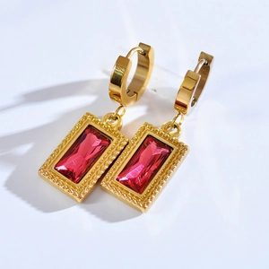 Macro detail of gold-plated hoop earring featuring a vibrant red rectangular zircon stone