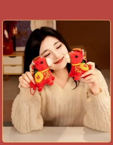 Lifestyle shot of red horse plush pendants held by model for Year of the Horse gift