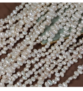 Detailed view of white freshwater baroque pearls strands on brown silk fabric background