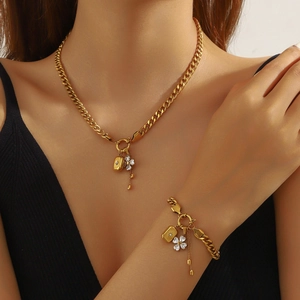 Golden necklace and bracelet set with clover charms and tassels worn by a model