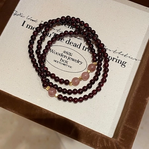 Close-up of garnet and strawberry quartz multi-layer beaded bracelet in a velvet gift box