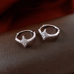 Detailed macro view of silver star earrings with zircon inlay on dark leather background