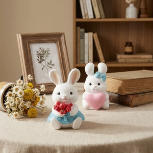Set of two decorative resin rabbit figurines with heart and tulip in a warm home setting