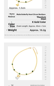 Detail view of gold steel necklace with matte butterfly and green heart zircon