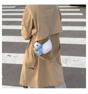 Detail of a white knitted duck crossbody bag with blue scarf on a trench coat
