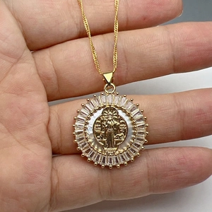 Macro shot of gold San Benito medal pendant with white mother of pearl and cubic zirconia