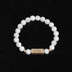 Macro shot of white marble stone bead bracelet with a golden Love engraved metal bar