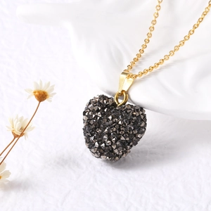Vue détaillée d'un pendentif coeur doré serti de cristaux gris sur une céramique