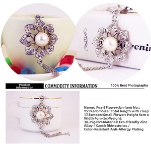 Macro detail of rhinestone flower pendant with large faux pearl and long silver tassels