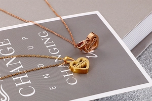 Macro detail of heart-shaped mama pendant necklaces in gold and rose gold finishes