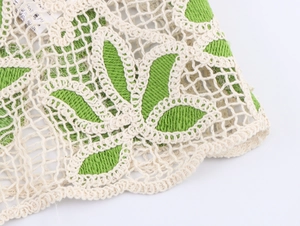 Détail de tissu en dentelle crochetée évidée avec broderie de feuilles vertes et maille