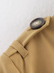 Detailansicht eines khakifarbenen Twill-Trenchcoats mit dunklen Schildpattknöpfen und Epauletten