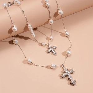 Elegant pearl bead necklace with a sparkling zircon encrusted cross pendant on pink stand