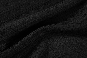 Detailed close-up of black ribbed knit fabric texture on a women's fitted dress