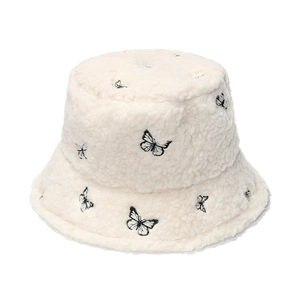 Close-up of fuzzy beige bucket hat with detailed black butterfly embroidery texture