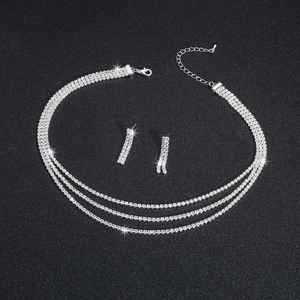 Detail of silver multilayer rhinestone necklace and tassel earrings on dark background