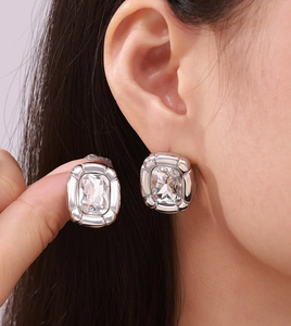 Close-up of model wearing silver square stud earrings with clear sparkling gemstones
