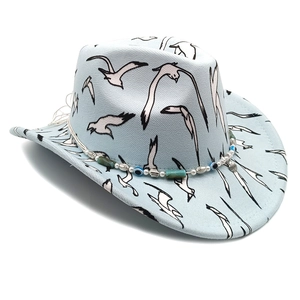 Detail of light blue wool cowboy hat featuring bird prints and beaded shell headband decoration