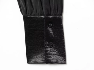 Detail of elegant black satin sleeve cuff with pleats and glossy round buttons