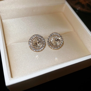 Detailed macro view of square zircon stud earrings with golden halo setting on satin