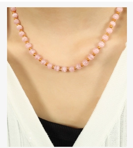 Close-up of elegant pink cat-eye bead necklace with gold spacers on a female model