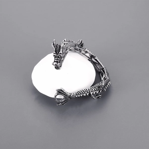 Dettaglio del bracciale drago punk con scaglie d'argento su supporto di pietra