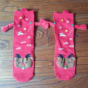 Detail of red Christmas socks with 3D reindeer arms and HO HO HO pattern on wood floor
