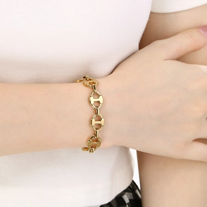 Close-up of golden stainless steel pig nose chain bracelet worn on a female wrist