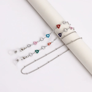 Detail of silver eyewear chain with colorful enamel hearts and lobster clasps on white pillar