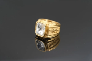 Macro shot of gold dragon ring with a large square clear gemstone on black mirror