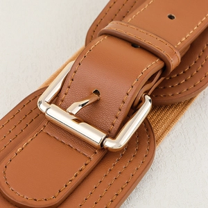 Detail of a wide elastic brown belt featuring a gold buckle and fine decorative stitching