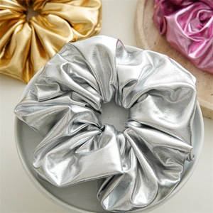 Close-up of a silver metallic scrunchie in a white bowl with detailed texture
