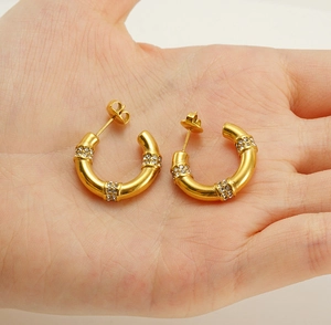 Close-up of C-shaped 18K gold-plated geometric earrings with triple rows of rhinestones