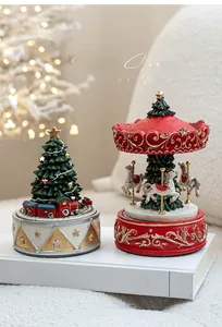 Detail of Christmas carousel music boxes with festive red and green ornaments on white books